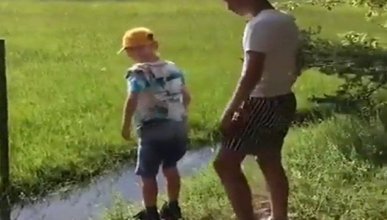 Erkek kardeşin su birikintisinden geçmesine yardım etmek