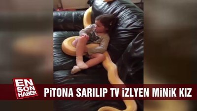 Pitona sarılıp televizyon izleyen minik kız