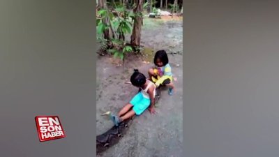 Piton yılanının üstüne binen çocuklar