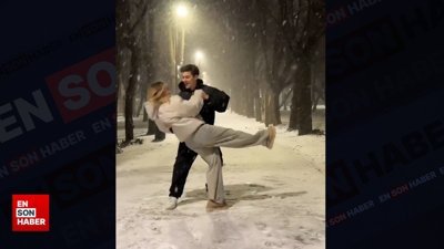 Genç çiftin kar yağışı altında romantik dansı