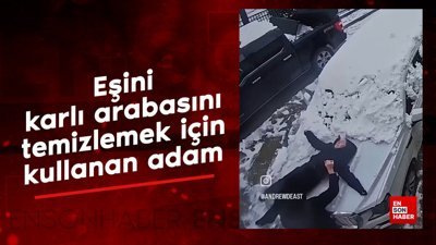 Eşini karlı arabasını temizlemek için kullanan adam