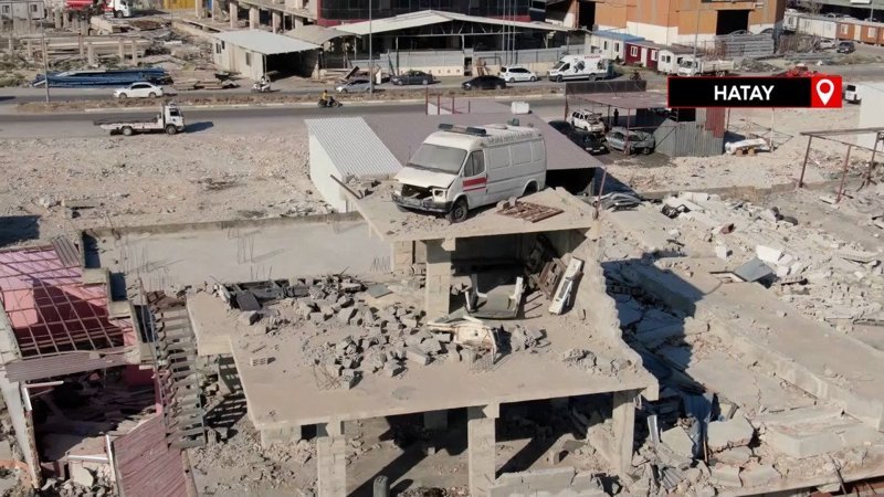 Depremde ağır hasar alan binanın çatısında duran minibüs görenleri şaşırtıyor