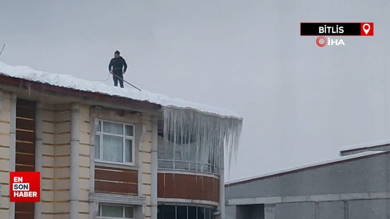 Beline bağladığı iple çatıda biriken kar yığınını temizledi